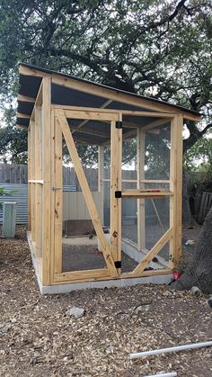 a chicken coop built into the side of a tree in front of a fenced in area