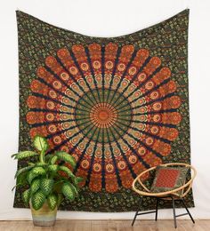 a tapestry hanging on the wall next to a chair and potted plant