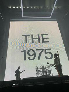 the 1970 band is performing on stage with their instruments in front of a large screen