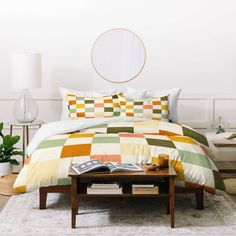 the bed is made up with multicolored checkerboard comforters and pillows