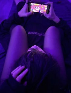 a person laying down with their legs crossed and holding a cell phone up to their face