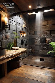 a bathroom with stone walls and wooden flooring next to a shower stall filled with plants