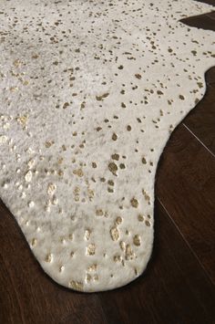 a white and gold area rug on top of a wooden floor