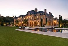 a large house with a pool in front of it at night time and lit up by lights