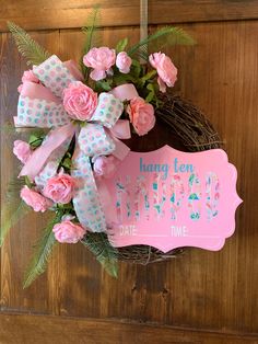 a wreath with pink roses and green leaves hanging on a door hanger that says happy birthday