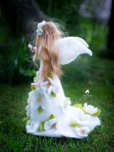 a doll is dressed in white and has long red hair, sitting on the grass