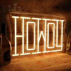 a neon sign that says hollywood next to some wine bottles and glasses on a table