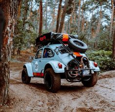 an old vw buggy is parked in the woods with its luggage on it's back