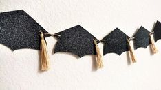 black graduation cap tassels hanging on a wall with gold tassels in the shape of bats