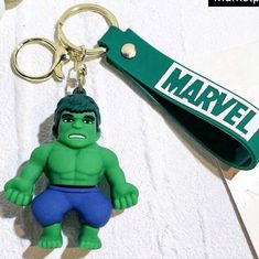 a green keychain with a cartoon character on it's side and a name tag attached to it