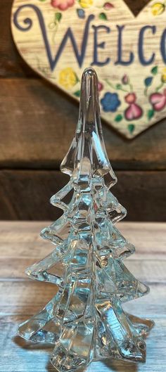 a glass christmas tree sitting on top of a wooden table