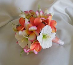 a bridal bouquet with pink and white flowers on top of a bed sheet,