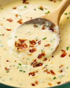 a wooden spoon in a white sauce with bacon and green onions on it's side