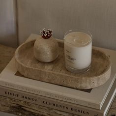 a candle sitting on top of a book next to a glass filled with milk in front of a stack of books