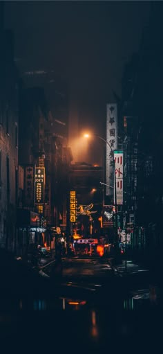 a dark city street at night with lights and signs on the side of the road