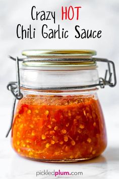 a jar filled with red sauce sitting on top of a table next to a spoon