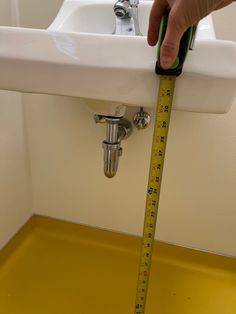 a person is measuring the height of a sink with a tape on it's edge