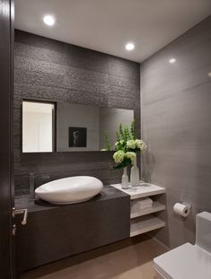 a white sink sitting next to a toilet in a bathroom under a mirror on the wall