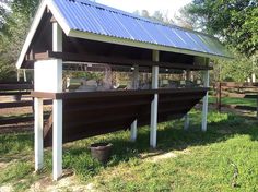 a large boat sitting on top of a grass covered field next to a fenced in area