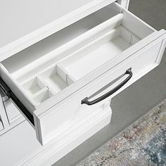 an open drawer on the side of a white cabinet with handles and drawers in it