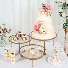 a table topped with three tiered cakes and cupcakes