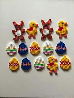 six different colored beads are arranged in the shape of chickens and eggs on a white surface