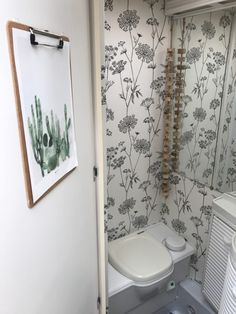 a bathroom with a toilet, radiator and wallpaper