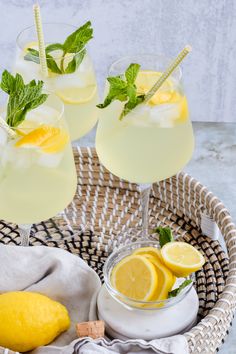 two glasses filled with lemonade sit on a wicker tray