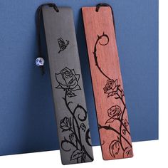 two wooden bookmarks with flowers and butterflies on them, one has a bead in it's ear