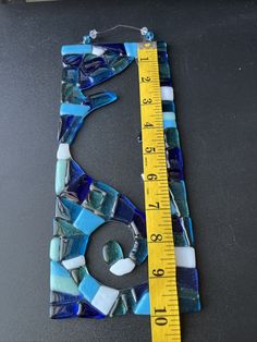 a piece of art made out of blue and white glass with a measuring tape next to it