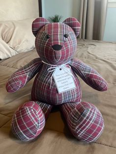 a teddy bear sitting on top of a bed next to a pillow with a tag