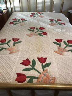 a quilted bedspread with red flowers on it