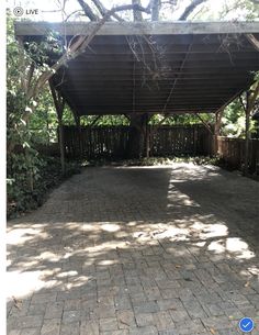 an outdoor covered patio with brick pavers and trees in the backgroung