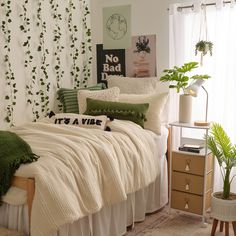 a bed with white sheets and green pillows in a room decorated with greenery on the walls