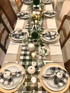 the table is set with black and white plaid napkins, silverware, candlesticks, and pumpkins