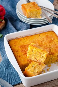 cornbread casserole in a white dish on a blue cloth with silverware