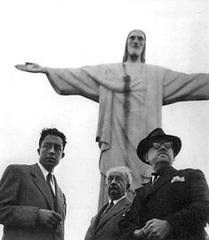 three men standing in front of a statue with the christ on it's back