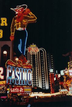 the las vegas casino sign is lit up at night with neon signs and buildings in the background