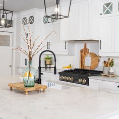 a kitchen with white cabinets and marble counter tops, along with an island in the middle