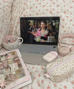 an open laptop computer sitting on top of a bed next to pillows and other items