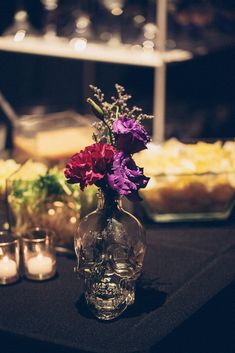 flowers in a vase sitting on a table with candles and food behind it at a party