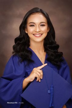 a woman in blue graduation gown posing for the camera with her finger on her hip