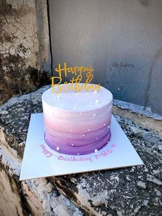 a purple and white cake sitting on top of a stone wall next to a door