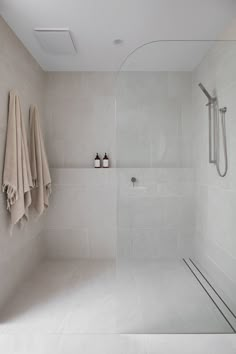 a white tiled bathroom with two towels hanging on the wall