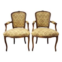 a pair of carved wood chairs with upholstered back and arm rests against each other