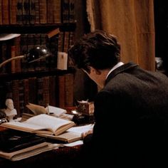 a man sitting at a desk in front of a bookshelf filled with books