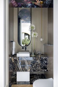 a bathroom with marble counter tops and an artful mirror above the sink in front of it