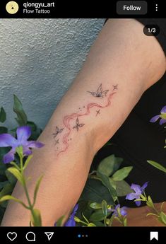 a woman's arm with a tattoo on it and purple flowers in the background