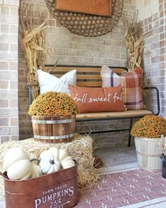 pumpkins and gourds are sitting in buckets on the porch with hay