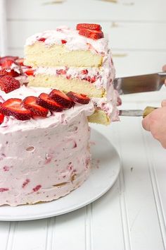 someone is cutting into a strawberry cake on a white plate